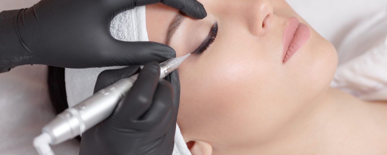 Cosmetologist making permanent makeup, close up. Tattooist making permanent make-up. Attractive lady getting facial care and tattoo. Permanent make-up tattoo at beauty salon