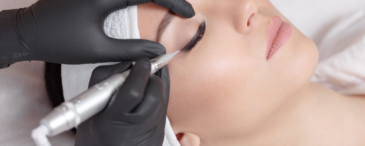 Cosmetologist making permanent makeup Cosmetologist making permanent makeup, close up. Tattooist making permanent make-up. Attractive lady getting facial care and tattoo. Permanent make-up tattoo at beauty salon