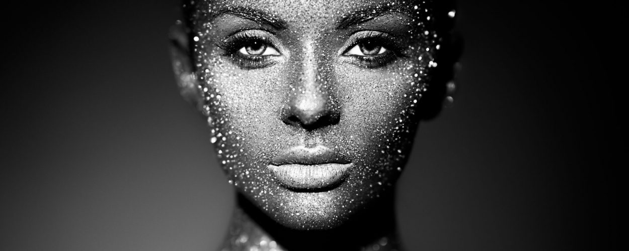 Fashion model woman in bright sparkles and lights posing in studio. Portrait of beautiful sexy woman. Art design glitter glowing make up. Black and white photography